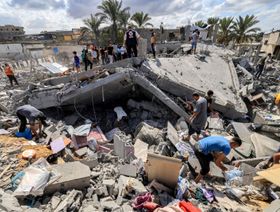أشخاص يفتشون أنقاض مبنى مدمر في خان يونس، جنوب غزة - المصدر: بلومبرغ