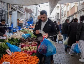 أحد السكان المحليين يعدّ أوراقاً نقدية أثناء تسوقه في سوق "فندق زاده" المفتوح للخضراوات في إسطنبول، وسط زحام المتسوقين والباعة، تركيا - بلومبرغ