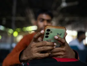 شخص يتفقد هاتفه الذكي أثناء امتحان توظيف لدى شركة تصنيع دراجات نارية في معهد التدريب الصناعي الحكومي في لكناو، أوتار براديش، الهند - بلومبرغ