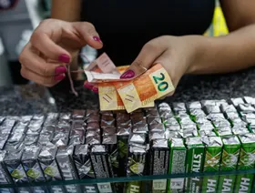 تاجرة تتسلم أوراقاً نقدية بالريال البرازيلي في متجر بمدينة ساو باولو - بلومبرغ