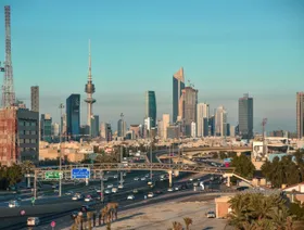 مبانٍ مكتبية وناطحات سحاب، بما في ذلك برج التحرير ، خلف الطريق السريع في مدينة الكويت، الكويت - المصدر: بلومبرغ