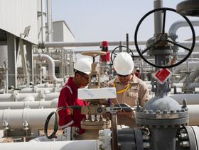 عاملان يتحققان من صمامات الأنابيب في حقل مجنون النفطي قرب البصرة. العراق - المصدر: بلومبرغ