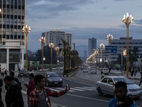 أشخاص يسيرون في أحد الشوارع المليئة بالأشجار المزروعة حديثاً والمنشآت المضاءة في أديس أبابا، إثيوبيا. - المصدر: أ. ف. ب