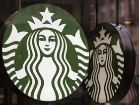 شعار "ستاربكس" على جدار زجاجي بأحد فروعها - بلومبرغ