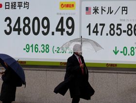 يمر المشاة أمام لوحة أسعار الأسهم التي تُظهر متوسط ​​مؤشر "نيكاي" وسعر الصرف بين الين الياباني والدولار الأميركي خارج مكتب وساطة في طوكيو. 3 أبريل 2025 - رويترز 