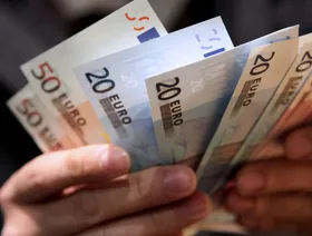 شخص يمسك بأوراق نقدية من فئتي 20 و50 يورو - بلومبرغ