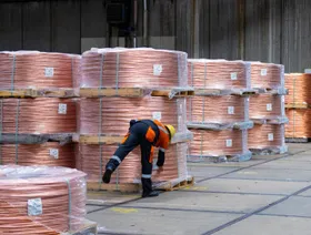 عامل يربط بكرات من أسلاك النحاس مخزنة في هامبورغ، ألمانيا - بلومبرغ