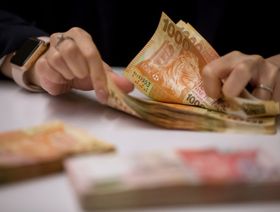 موظفة تعدّ أوراقًا نقدية من فئة ألف دولار هونغ كونغي في مقر بنك "هانغ سنغ" المحدود في هونغ كونغ. 16 أبريل 2019 - بلومبرغ