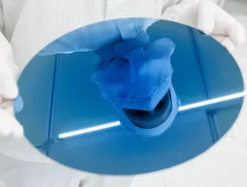 انعكاس صورة موظف على رقاقة سيليكون يحملها داخل مصنع لأشباه الموصلات - المصدر: بلومبرغ