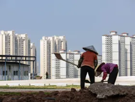 عاملان أمام المباني السكنية في مشروع قصر فينيكس الذي تطوره "كانتري غاردن" في الصين - المصدر: بلومبرغ