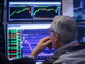 متداول يراقب شاشة أسعار الأسهم في بورصة نيويورك - بلومبرغ
