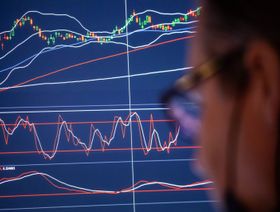 متداول ينظر إلى شاشة تعرض حركة الأسهم - المصدر: بلومبرغ