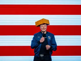 إيلون ماسك رئيس مجلس إدارة منصة "إكس" للتواصل الاجتماعي ومؤسس "إكس إيه آي" يتحدث خلال إحدى الفعاليات مرتدياً قبعة على شكل قطعة جبن - بلومبرغ