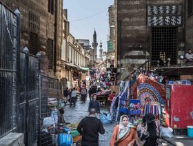 مجموعة من المارة وباعة جائلين بشارع به مباني أثرية قديمة في مصر - الشرق/بلومبرغ