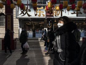 مارة يرتدون أقنعة طبية بينما يسيرون في أحد شوارع الصين - المصدر: بلومبرغ