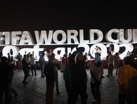 زائرون يلتقطون صوراً بجانب شارة لكأس العالم 2022 لكرة القدم على كورنيش الدوحة، قطر. - المصدر: بلومبرغ