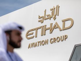 رجل يعبر من أمام شعار الاتحاد للطيران في أحد معارض الطيران بإمارة دبي، الإمارات العربية المتحدة - المصدر: بلومبرغ