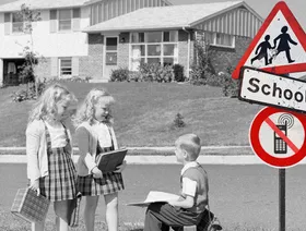 أطفال بالزي المدرسي بجوار لافتة تحمل شعار ممنوع استخدام الهواتف المحمولة - بلومبرغ