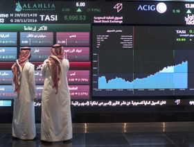 شخصان ينظران إلى لوحة إلكترونية ضخمة تعرض أسعار الأسهم داخل مبنى سوق الأسهم السعودية (صورة أرشيفية) - المصدر: بلومبرغ