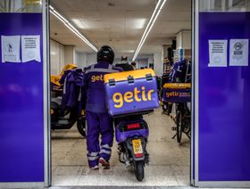 عامل توصيل من "غيتر" يقود دراجة بخارية إلى سوبر ماركت لتوفير الطلبات - المصدر: بلومبرغ