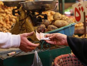سيدة تدفع ثمن مشتريات بالجنيه المصري في سوق المنيرة للمواد الغذائية في منطقة إمبابة بالجيزة، مصر - المصدر: بلومبرغ
