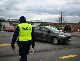 أفراد شرطة ينسقون عملية مرور آلاف السيارات التي تصل من جميع أنحاء أوروبا لنقل ذويهم في ميدكيا، ببولندا على الحدود الأوكرانية، بتاريخ 25 فبراير 2022 - المصدر: غيتي إيمجز