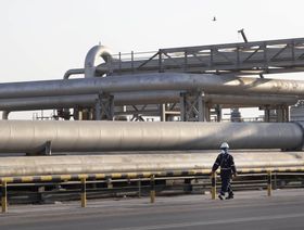 عامل يسير قرب أنابيب لنقل النفط في محطة لمعالجة الخام تابعة لـ"أرامكو السعودية" في بقيق، المملكة العربية السعودية - المصدر: بلومبرغ