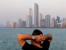 شخص جالس ينظر إلى أفق إمارة أبوظبي، الإمارات العربية المتحدة - المصدر: بلومبرغ