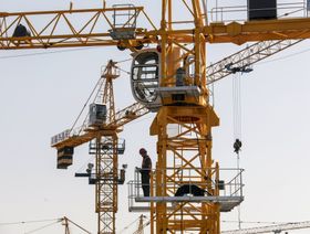 عامل يقف على رافعة في موقع بناء مشروع منتجع "سوناك"، الذي طورته شركة "سوناك تشاينا هولدينغز"، في هايان، مقاطعة زيجيانغ، الصين. - المصدر: بلومبرغ