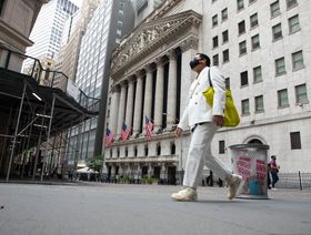 أحد المشاة يرتدي قناعاً وقاياً يمر أمام بورصة نيويورك، الولايات المتحدة - المصدر: بلومبرغ