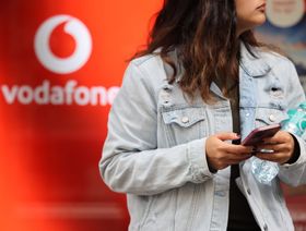 شابة تحمل هاتفاً ذكياً داخل متجر تابع لشركة "فودافون غروب" في برشلونة، إسبانيا - المصدر: بلومبرغ