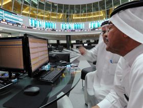 شخصان أمام شاشة تداول داخل بورصة البحرين - المصدر: بلومبرغ