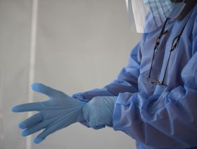 أحد العاملين في مجال الرعاية الصحية يرتدي قفازات واقية لليد. - المصدر: بلومبرغ