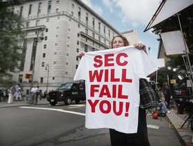 امرأة ترفع قميصاً يحمل انتقاداً لهيئة الأوراق المالية والبورصات الأميركية خلال جلسة الحكم على برنارد مادوف في 2009 - المصدر: غيتي إيمجز