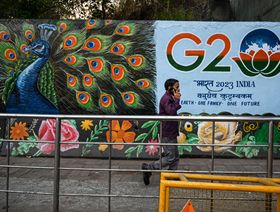 شخص يعبر من أمام لافتة تحمل شعار مجموعة العشرين في نيودلهي، الهند، بتاريخ 2 مارس 2023 - المصدر: بلومبرغ