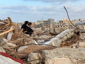 شابان يجلسان فوق ركام أحد المنازل يوم 20 سبتمبر 2023، بعد أكثر من أسبوع على الفيضان الذي شهدته مدينة درنة شرقي ليبيا - المصدر: غيتي إيمجز