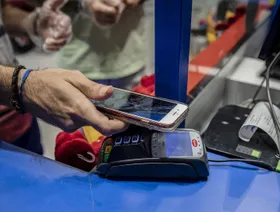 زبون يجري معاملة دفع إلكترونية عبر هاتف ذكي ونقطة بيع - المصدر: بلومبرغ