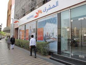 مشاة يعبرون من أمام أحد فروع بنك المشرق في إمارة دبي - المصدر: رويترز