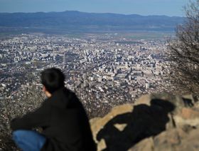 شخص يجلس على حافة جبل مطل على العاصمة البلغارية صوفيا. - بلومبرغ