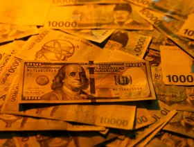 أوراق نقدية من الوون الكوري الجنوبي إلى جانب ورقة من فئة 100 دولار أميركي - بلومبرغ