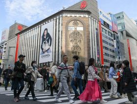 متسوقون  يسيرون في شارع حيوي بمنطقة جينزا في طوكيو مع وجود متاجر كبرى مثل ميتسوكوشي ولافتات إعلانية فاخرة مثل شانيل - بلومبرغ