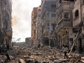 رجل يحمل أسطوانة غاز أثناء عبوره بين الحطام في حي تعرض للقصف في مخيم جباليا في غزة، في 11 أكتوبر 2023 - المصدر: بلومبرغ