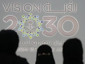 سيدات يقفن أمام شعار رؤية 2030 خلل مؤتمر بالعاصمة السعودية الرياض (أرشيفية) - المصدر: بلومبرغ