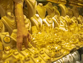 تاجر يرتب مجوهرات من الذهب في واجهة متجره - المصدر: بلومبرغ