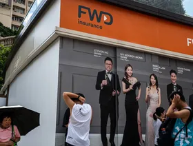 مارة أمام إعلان لشركة "إف دبليو دي غروب هولدينغز" للتأمين في هونغ كونغ - بلومبرغ