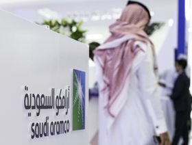 رجل سعودي يدخل إلى إحدى الفعاليات وإلى يساره شعار شركة أرامكو السعودية - المصدر: بلومبرغ
