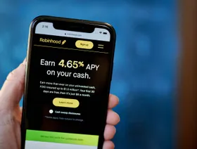 شخص يمسك هاتفاً ذكياً يظهر عليه الموقع الإلكتروني لـ"روبن هود" - بلومبرغ