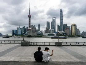 شخصان يجلسان أمام مباني حي لوجياتسوي المالي، منطقة بودونغ، شنغهاي، الصين - بلومبرغ