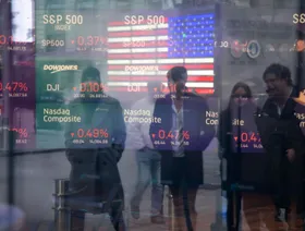 انعكاس صورة أشخاص يتفحصون بيانات ومعلومات عن سوق الأسهم عند مبنى بورصة ناسداك في نيويورك، الولايات المتحدة - المصدر: بلومبرغ