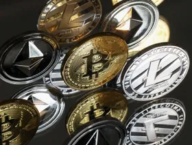 مسكوكات رمزية تحمل شعارات العملات المشفرة "بتكوين" و"إيثير" و"لايتكوين" - المصدر: بلومبرغ